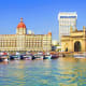 Mumbai waterfront with Gateway of India arch, historic colonial buildings, and fishing boats on Arabian Sea
